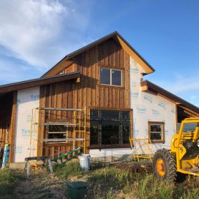 Barn-style shop/garage/guest house in the process of installing cedar siding. The construction site shows the ongoing work to beautify the structure with the elegant and timeless appeal of cedar siding.