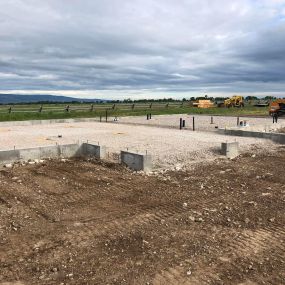 Completed foundation with a gravel floor on a prairie, showcasing a clean construction site ready for further progress.