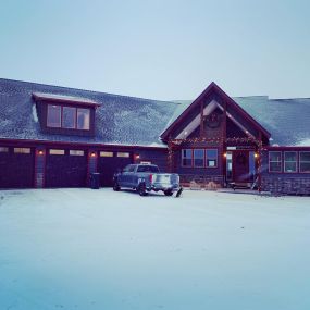 Modern Western home with attached three-car garage. Snow-covered surroundings. Truck parked in the front.