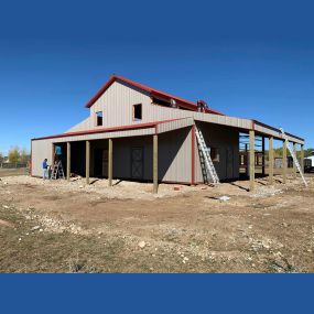 Newly built barn-style shop, nearing completion. Grey metal siding complements the vibrant red roof.