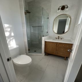 Bathroom remodel with frameless shower doors,, marble tile floors and brass faucets