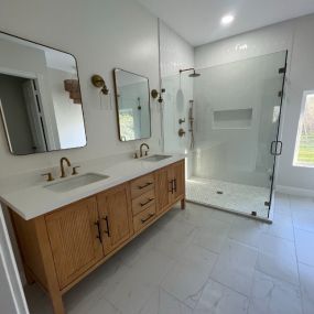 Bathroom remodel with frameless shower doors, double vanity with granite countertops, marble tile floors and teak cabinetry