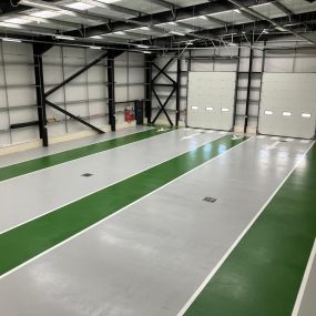 Grey resin floor with green gangways installed at a vehicle storage warehouse in Hull, UK