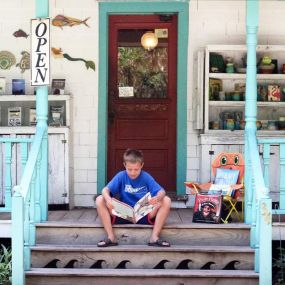 Child reading book on front steps of Books to be Red