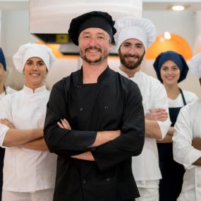 Proud multi ethnic team of restaurant chef, sous chefs, cooking assistants and caterers looking for a laundromat in Largo, FL