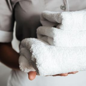 Commercial Wash/Dry & Fold in Largo, FL. Close up of a young hotel maid holding clean folded towels.