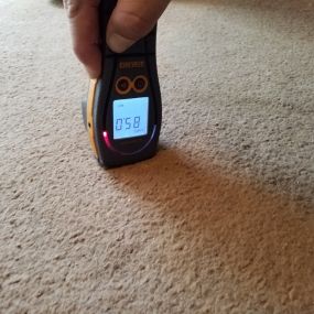 Utilizing a moisture meter to measure hidden moisture that may be behind walls after water damage.