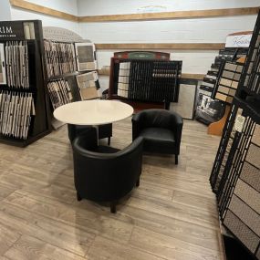 A room at USA Flooring Durham features a table and chairs surrounded by various samples, creating a welcoming and immersive environment for customers.