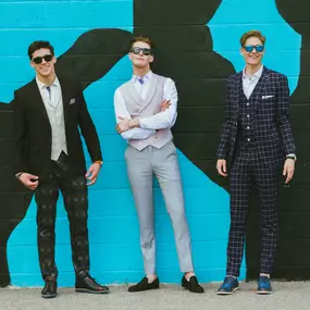 Sapien Designs Multimedia Studios has developed this image showcasing three men in stylish suits against a vibrant mural, highlighting modern fashion trends.