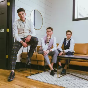 This image, developed and edited by Sapien Designs' Marketing Digital SEO, showcases three individuals in a modern office setting, emphasizing professional attire and a stylish workspace.