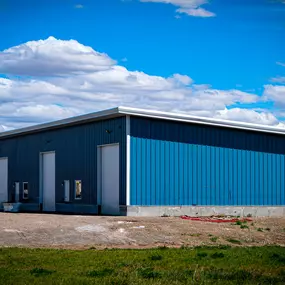A newly completed 8,000 SQFT steel fabrication machine shop, expertly constructed by Steel Concepts, Inc. for UpFab LLC. This facility, showcased by its durable blue metal siding and multiple large white overhead access doors, is designed for optimal efficiency, precision, and long-term growth, supporting high-capacity operations and specialized machinery with robust structural integrity.