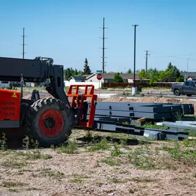 This image shows a crucial piece of equipment, a Skyjack SJ843 TH telehandler, on the construction site of a Steel Concepts project. The telehandler is situated near neatly stacked steel beams, indicating preparations for structural erection. This site is for a 12,600 square foot Regional Gym in Twin Falls, ID, where Steel Concepts is operating as the General Contractor for this retail category project. The scene conveys the organized progression of the construction phase.
