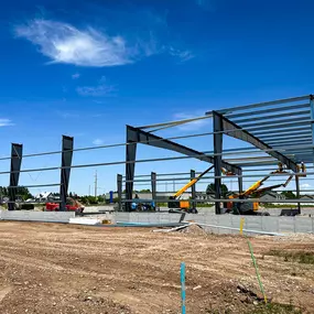 Professional image showcasing the steel framework construction of the Gwinner Airplane Hangar by Steel Concepts. The durable steel structure is prominently featured against a clear sky, highlighting the precision and scale of the build.