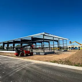 This image captures the ongoing steel building erection for Impel Transport, a project expertly handled by Steel Concepts. The photograph highlights the impressive steel frame of the future facility, with columns, beams, and roof purlins already in place, showcasing the rapid progress of the construction. Construction equipment, including telehandlers and boom lifts, are visible on site, actively assisting in the assembly process.