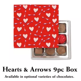 A Valentine's Day-themed table featuring Florence's Exquisite Chocolates in Rexburg, Idaho. At the center is a beautifully packaged red box of 9 chocolates adorned with heart and arrow designs, labeled 