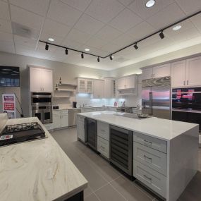 Appliance showroom with white cabinetry and stainless steel appliances