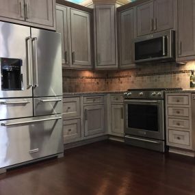 kitchen appliance showroom with wooden cabinetry, dark flooring, a stainless steel fridge, stainless steel oven, and microwave