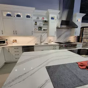 Kitchen appliance showroom with white cabinetry and white marble countertop