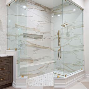 Shower Remodel featuring Kohler plumbing fixtures in gold finish, frameless glass, and a built-in wall niche.