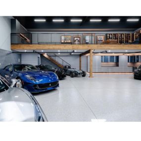 Our team of experts is here to help you choose the perfect storage options for your garage as seen in this upper garage loft & we specialize in beautiful commercial grade epoxy floors.
