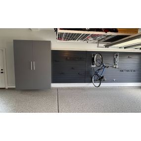 Garage organization optimized with custom cabinets, slat wall with bike racks, over head storage racks and it all looks great on this durable epoxy floor coating.