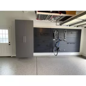 Garage organization optimized with custom cabinets, slat wall with bike racks, over head storage racks and it all looks great on this durable epoxy floor coating.