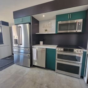 stainless steel refrigerator, dishwasher, range, and microwave on display with blue cabinets