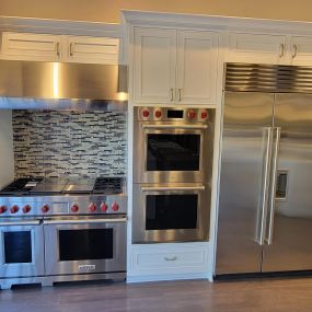 kitchen showroom with stainless steel appliances on display and white cabinetry