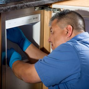 A technician performs Sub-Zero repair on an ice-maker.