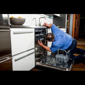 A technician checks something in the dishwasher while performing an ASKO repair.