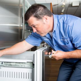 A technician checks the door alignment on a Sub-Zero refrigerator after a successful repair.