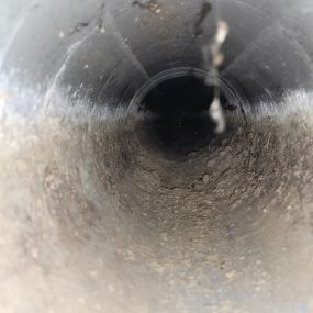An air duct prior to professional cleaning filled with dust and debris