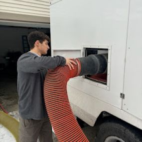 Hooking up the air vent vacuum hose to the work truck.