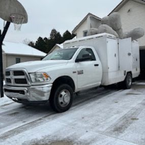 A truck with duct cleaning equipment parked outside of a home.