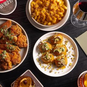 Overhead shot of Dry Rubbed Chicken Wings, Spicy Triple Cheese Mac ‘N’ Cheese and Artichoke & Goat Cheese Croquettes