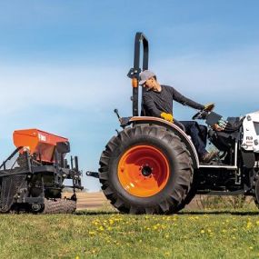 Man driving a Bobcat Compact Tractor looking backward at three-point hitch