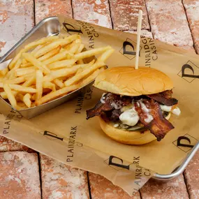 A mouthwatering Bacon Cheddar Burger served at the Sportsbook restaurant and bar at Plainridge Park Casino in Plainville, Massachusetts. 60z brisket chuck patty, pickles, thick bacon, steamed onion, cheddar, aioli, on a potato roll.