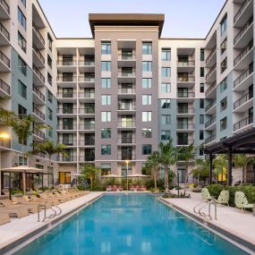 Pool with sundeck and cabanas surrounded by lush landscaping at Camden Atlantic in Plantation, Florida.