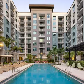 Pool with sundeck and cabanas surrounded by lush landscaping at Camden Atlantic in Plantation, Florida.