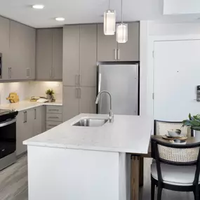 Kitchen with island, stainless steel appliances, modern latte color cabinets, quartz countertops, and glossy tile backsplash