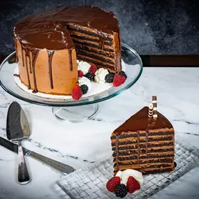 Chocolate Tower Cake, an 8 layer amaretto chocolate cake with Callebaut chocolate butter cream frosting. Garnished with seasonal berries, chocolate shavings, and chocolate sauce.