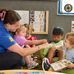 A childcare teacher reading to toddlers at New Horizon Academy Parker.