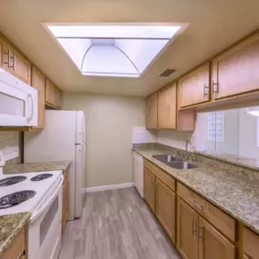 Kitchen with Dark Wooden Cabinets, White Appliances, and Overhead Lighting