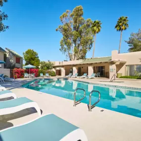 View of Soothing Blue Pool Surrounded by Blue Lounge Chairs in front of Resident Building