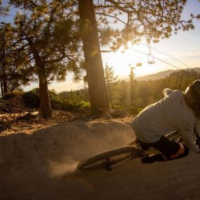 A mountain biker riding through a dirt berm during a Snow Valley Twilight Session evening.