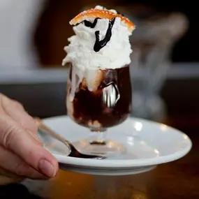 World's Smallest Ice cream sundae with deluxe vanilla ice cream, homemade hot fudge, scratchmade whipped cream, chocolate sauce and an orange peel