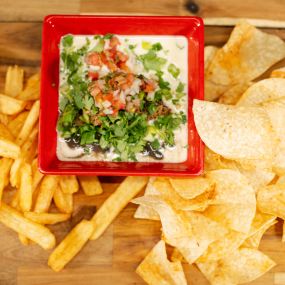 Misfit Dip - Charro black beans, green chili queso, with smoked pulled pork, green onion, cilantro, served with our signature chili cumin tortilla chips.