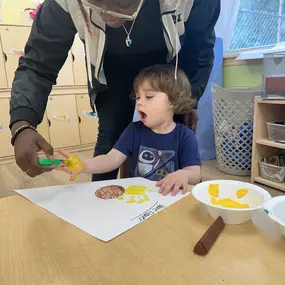 Guiding creativity! The teacher assists kids in making their art come to life, encouraging individual expression.