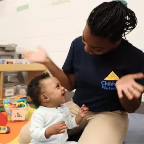 A caring teacher engaging with a child in the classroom, providing guidance and support during learning activities.