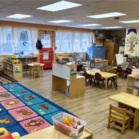 A colorful learning center designed for young children, with play areas, small tables, and engaging educational materials that encourage exploration and creativity.
